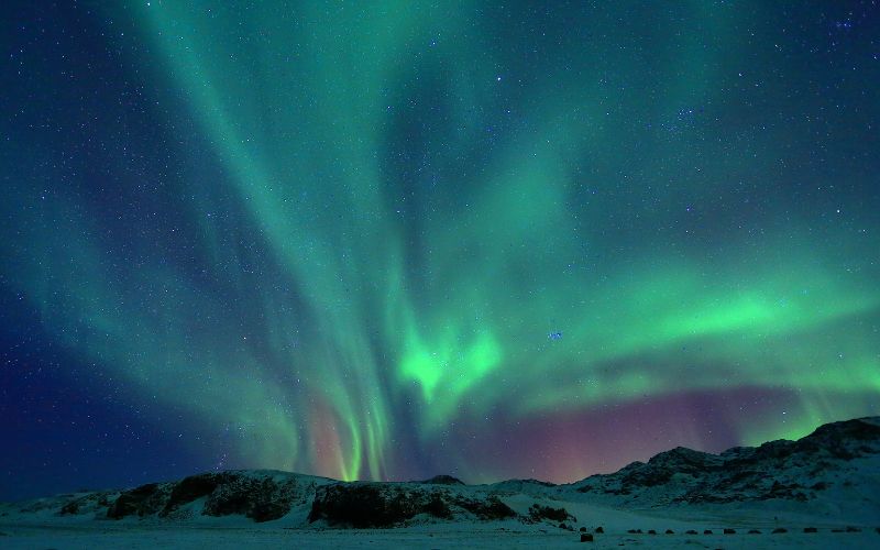 The northern lights making the night sky glow with hues of green.