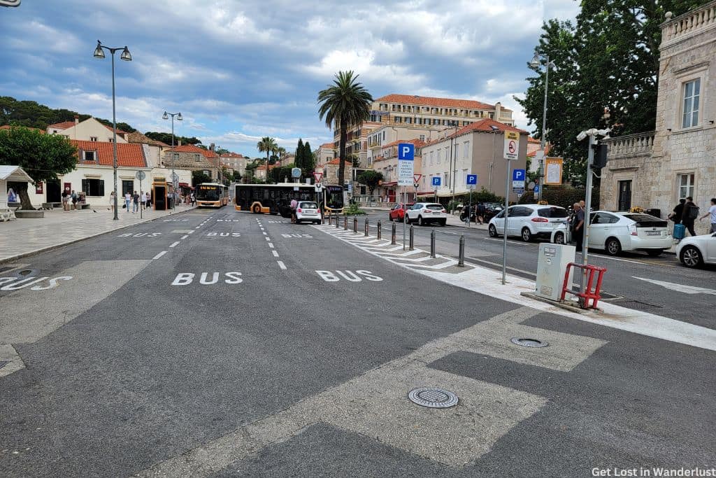 A busy street in Dubrovnik filled with cars and buses. The photo also shows parking signs.