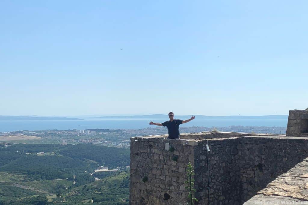 Dylan on a tower at Klis Fortress with panoramic views of Split and the Adriatic Sea in the distance