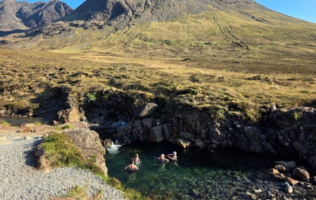 People swimming in the turquoise water at the Fairy Pools on the Isle of Skye.