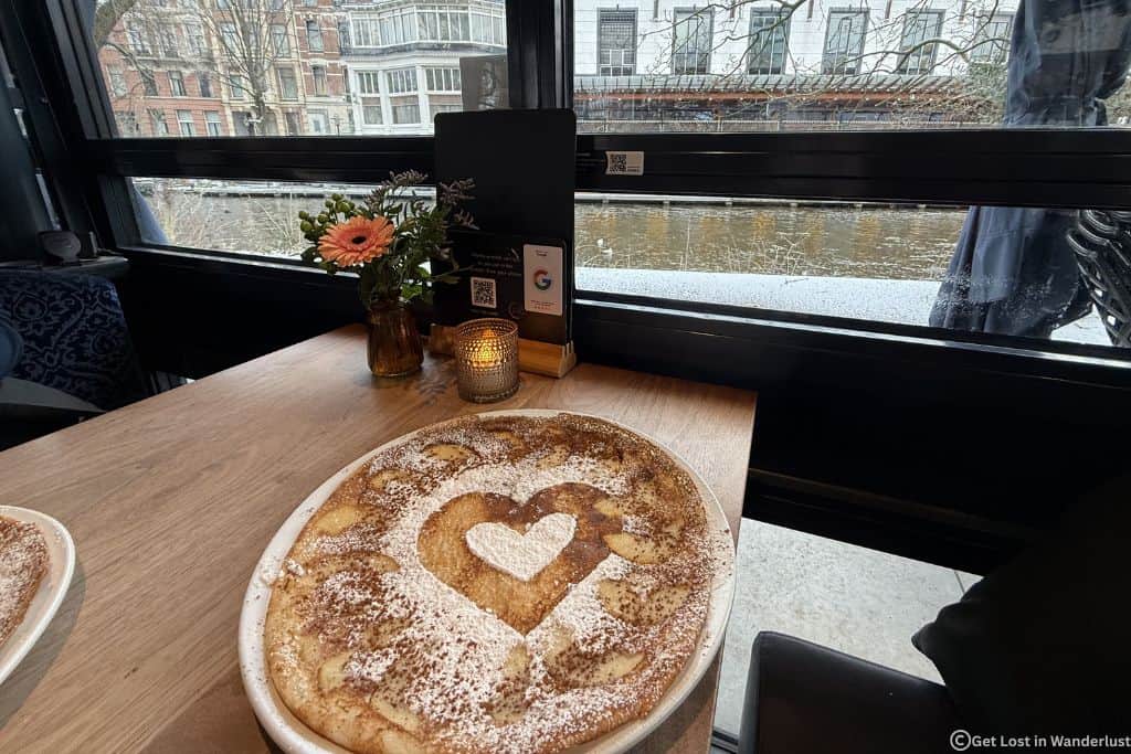 Pancake with a heart on it, with a view of the Amsterdam canal in the background.