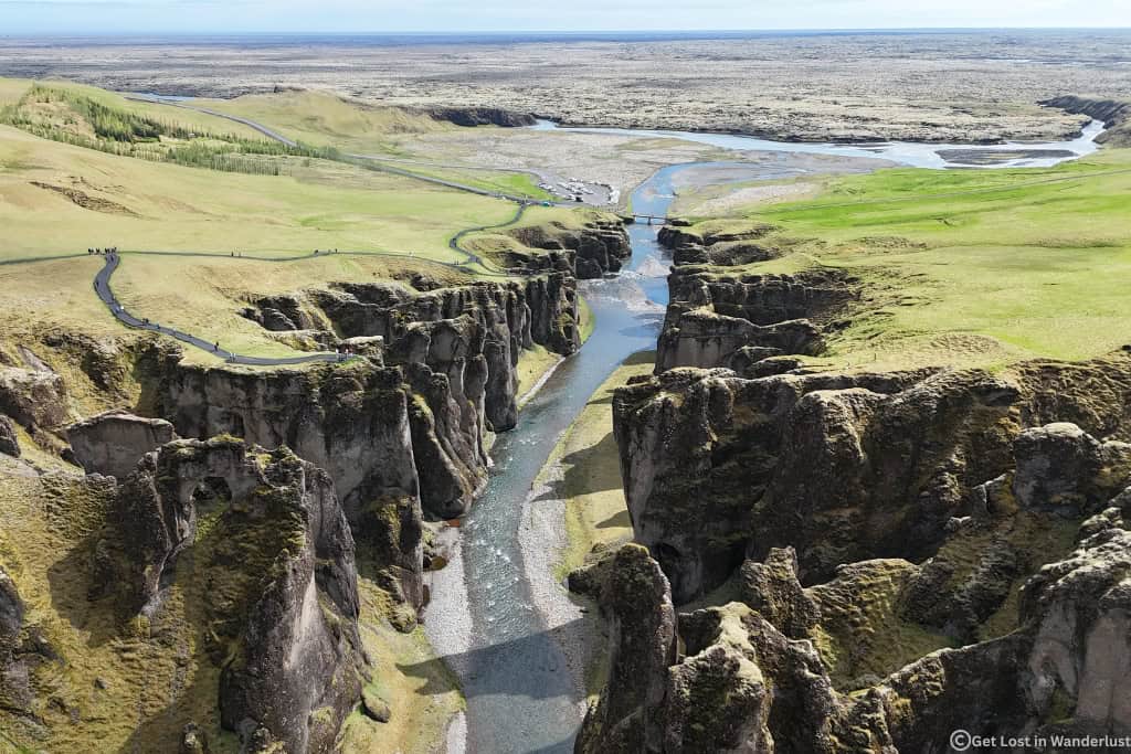 Fjaðrárgljúfur Canyon in South Iceland with a winding river flowing through dramatic moss-covered cliffs.
