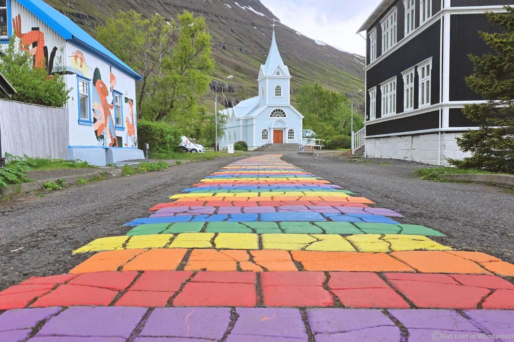 Seyðisfjörður, featuring the iconic rainbow street and blue church. If you love photography, charming villages, and hiking then Seyðisfjörður is a perfect choice for where to stay in East Iceland.