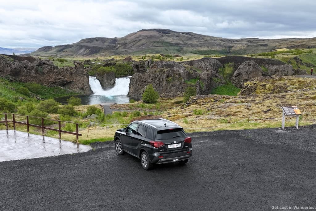 Lava rental car parked in front of a waterfall while doing a Ring Road trip in Iceland.
