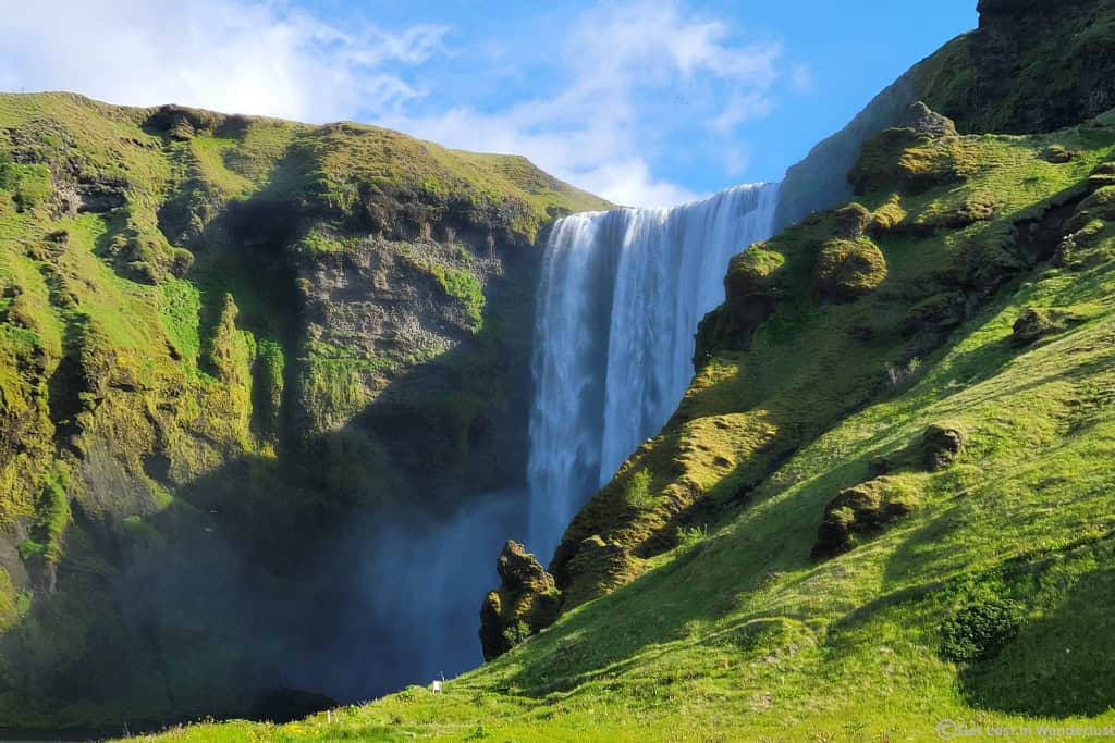 Skógafoss Waterfall in South Iceland with lush green cliffs and a powerful cascade, located along Iceland's Ring Road.