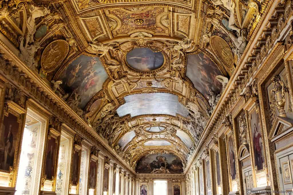 Ornate Galerie d’Apollon inside the Louvre Museum, featuring gilded details, painted ceilings, and historic architecture.