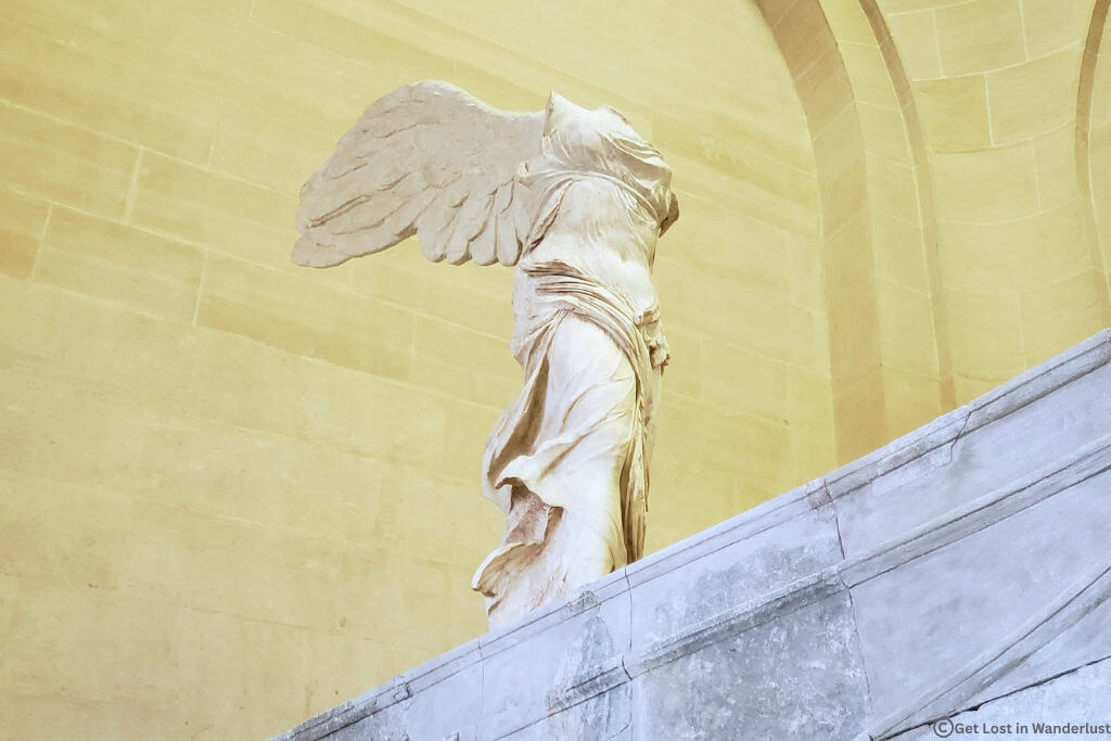 Winged Victory of Samothrace displayed at the top of the Daru staircase inside the Louvre Museum in Paris.