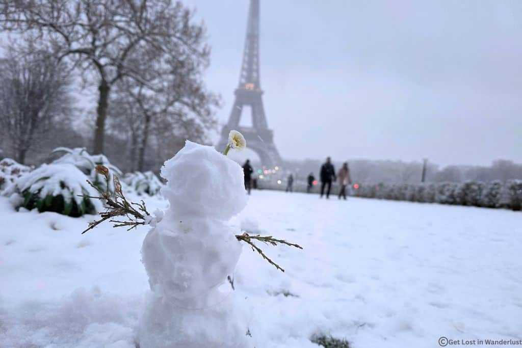 Small snowman in front of the Eiffel Tower after snowfall in Paris