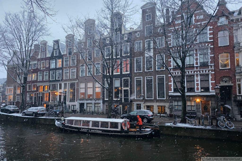 Canal in Amsterdam’s Nine Streets neighborhood, with historic canal houses and a tour boat passing by.