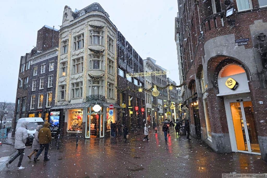Snow falling along Kalverstraat near Muntplein in Amsterdam’s Canal Belt, one of the safest areas to stay in Amsterdam.