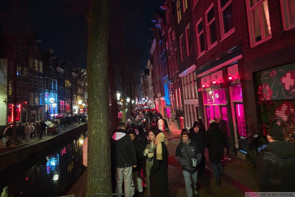 Amsterdam’s De Wallen Red Light District at night, with crowded canal-side streets.