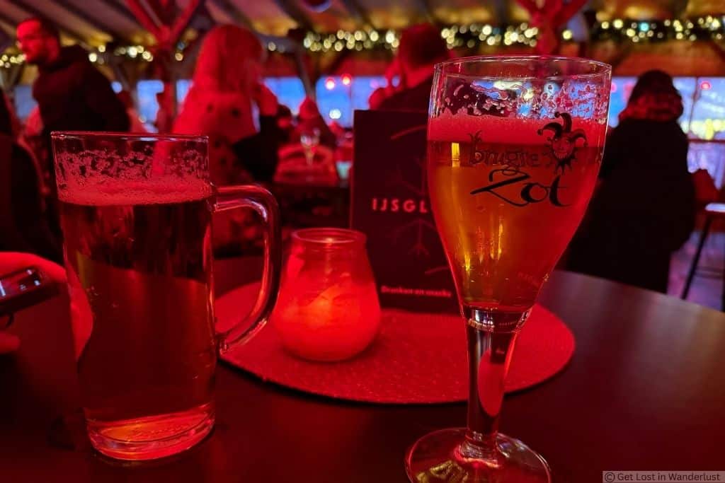 Belgian beer served inside the festive Bruges Winter Glow ice rink bar, surrounded by Christmas lights.