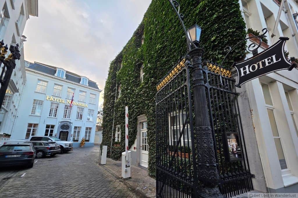 Entrance to Hotel Navarra in Bruges, Belgium, with its ivy-covered historic building and gated courtyard.