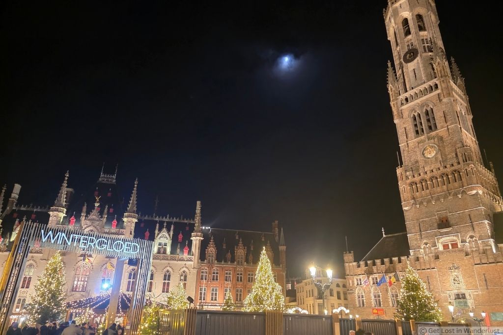 Bruges Winter Glow at night in Markt Square with illuminated Christmas trees, festive lights, and the Belfry of Bruges.