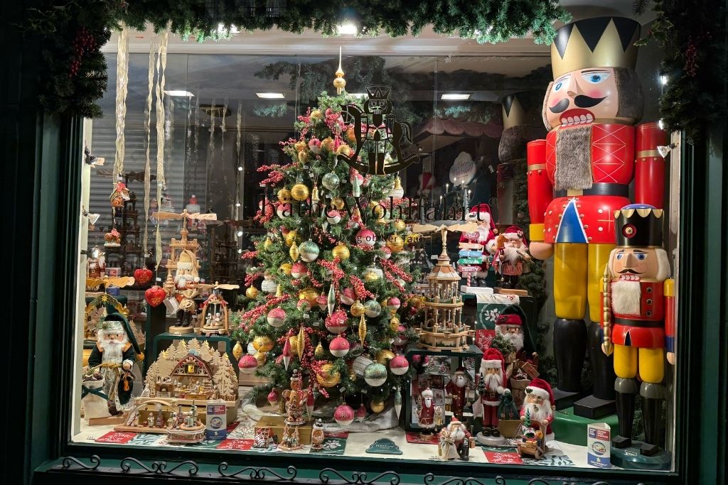 Christmas shop window in Bruges with a decorated tree, oversized nutcracker figures, Santas, and traditional holiday ornaments.