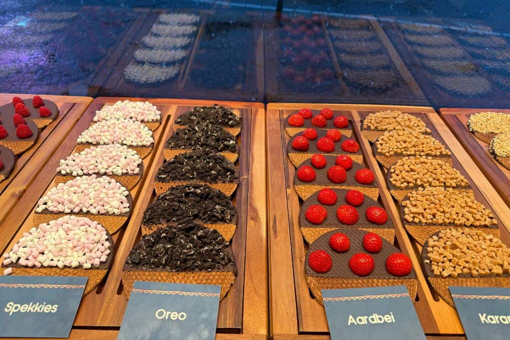Assorted stroopwafels topped with marshmallows, cookies, strawberries, and caramel at a shop in Amsterdam.